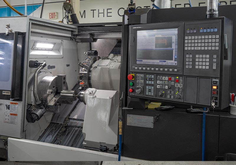 A CNC machine with an open door showing the workspace and control panel with various buttons and a digital display.